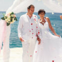 Friends throw petals on happy newlyweds while they walk to the wedding altar at beach